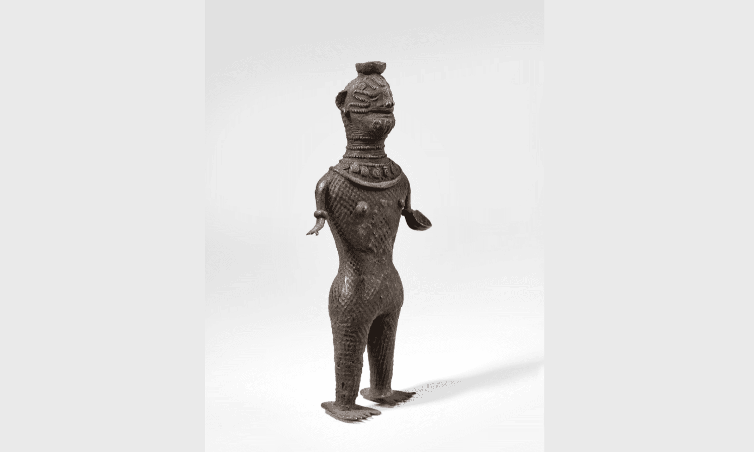 Estatuilla femenina tatuada con un bol sobre la cabeza y otro en la mano izquierda