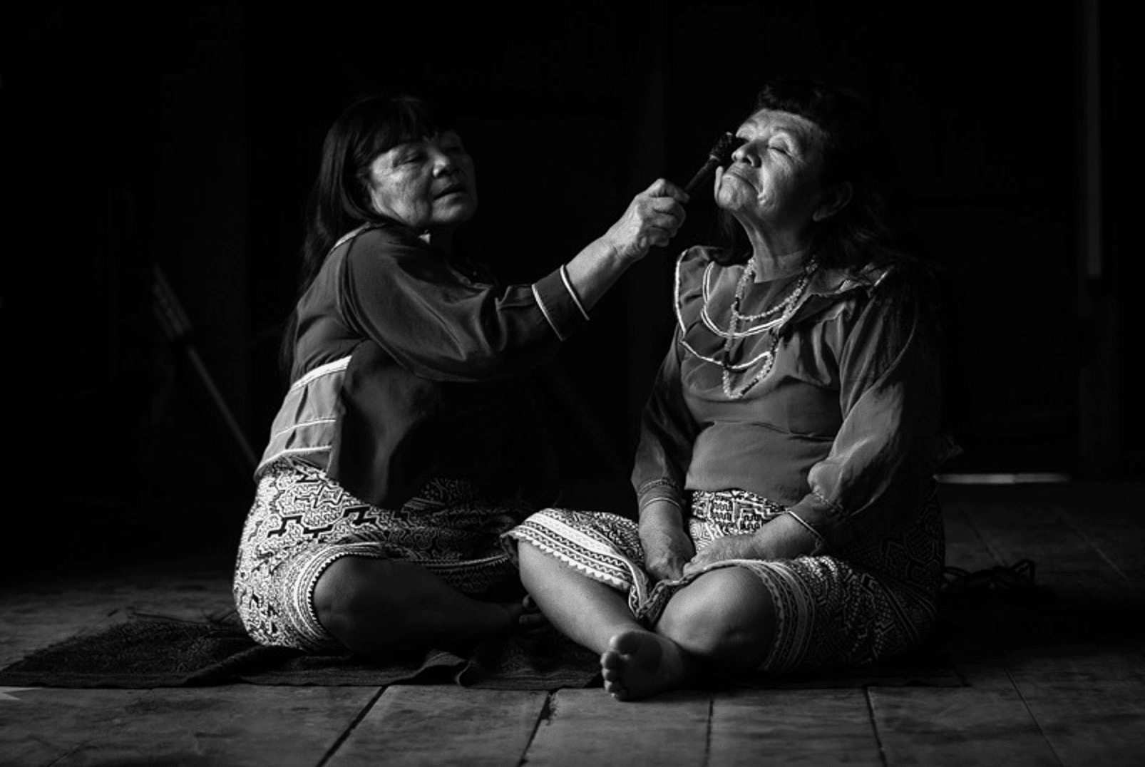 Mujeres pintándose el kené en el rostro, con tinte vegetal. Yarinacocha, Ucayali. 2022